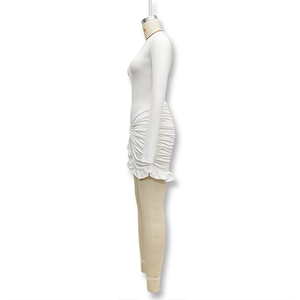 Detalle de un vestido blanco de manga larga con fruncido lateral y dobladillo volante