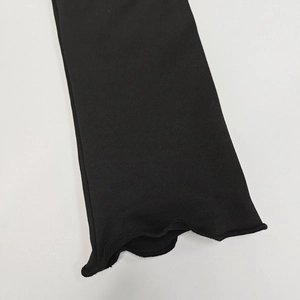Détail d'une robe noire à manches longues avec poignets à bords ondulés et texture tricot