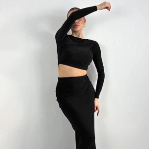 Detail of black two-piece set featuring crossover ruching on crop top and maxi skirt
