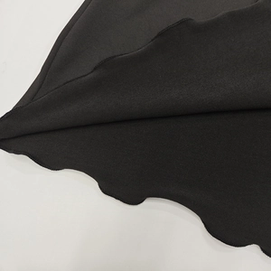 Gros plan sur l'ourlet noir à bords ondulés avec couture surjetée dense de la robe