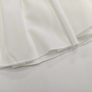 Vue macro d'un tissu blanc en polyester montrant l'ourlet plissé et les coutures
