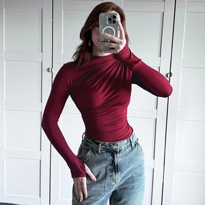 Close-up of wine red slim-fit turtleneck top with diagonal pleated texture and thumbholes