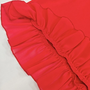 Detailed macro view of vibrant red chiffon ruffles with precise hem stitching on dress