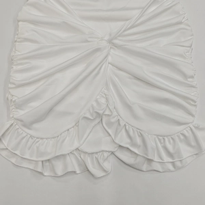 Detalle de vestido corto blanco con nudo retorcido frontal y elegante dobladillo de volantes