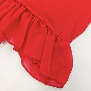 Detailed close-up of vibrant red knit fabric with delicate chiffon ruffle hem and stitching