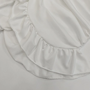Vista detallada de la textura de tela blanca con elegante dobladillo de volantes y costura