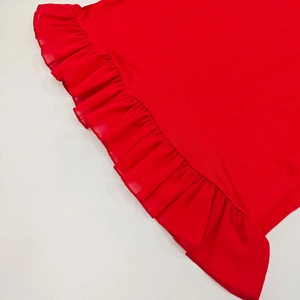 Close-up detail of the ruffled hem and fine stitching on a red bodycon dress