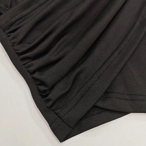 Detailed close-up of the black ruched fabric and double-needle coverstitch on the garment