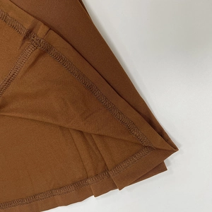 Gros plan détaillé montrant la couture à double aiguille sur l'ourlet de la robe marron