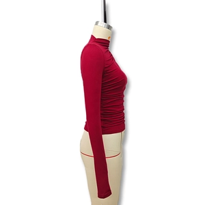 Detail view of burgundy ruched slim-fit turtleneck top with textured knit fabric