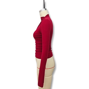 Side view showing the slim fit silhouette and draped waist detail of the red high neck top