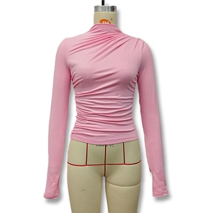 Detail of pink long-sleeved turtleneck top featuring textured ruched fabric design