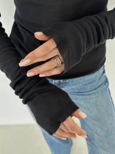 Detail view of black knit top featuring sheer flared sleeves and elegant stacked rings