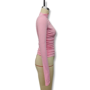Detail of pink long sleeve turtleneck top featuring ruched sides and slim fit fabric