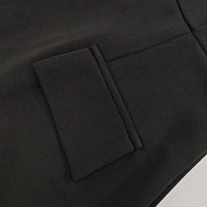 Detail shot of black knit dress showing precision stitching on the pocket flap