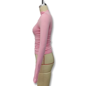 Detail of pink mock neck long sleeve top with slim-fit ruching on a mannequin