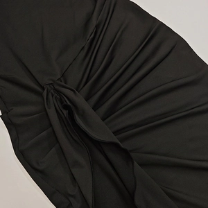 Close-up of gathered black fabric detail with center knot design on bodycon dress