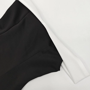 Detalle de un vestido negro y blanco con hombros descubiertos y cuello vuelto blanco ancho