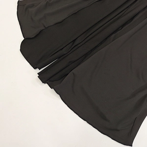 Close-up of black knitted fabric texture and flat lockstitch hem on the slim-fit dress