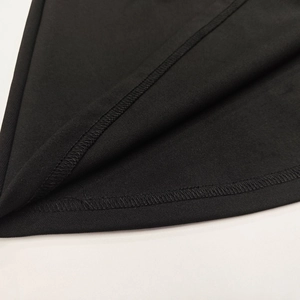 Detail of reinforced double-needle stitching and overlock edge on black knit dress