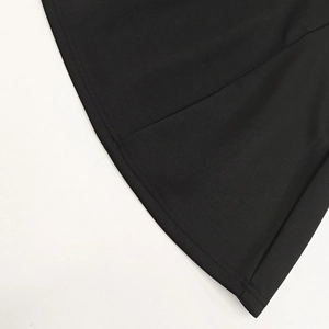 Détail de l'ourlet à double couture sur une robe trapèze noire avec une texture de tissu lisse