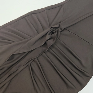 Detail of chocolate brown knit dress featuring central knot and ruched pleat design