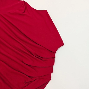 Close-up of red ruched fabric detailing on a slim fit turtleneck long sleeve top