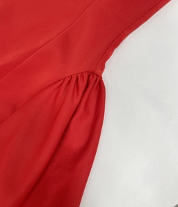 Detalle de cerca de tela roja con textura tejida fina y elegantes pliegues fruncidos