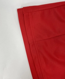 Primer plano detallado que muestra la costura de doble aguja en el dobladillo rojo