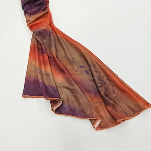 Detailed close-up of gradient ruched fabric with wavy ruffle hem in purple and orange tones