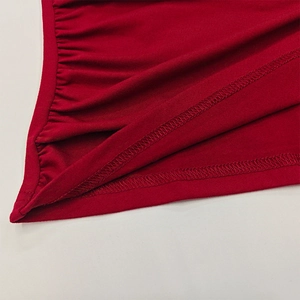 Detailed close-up of red ruched fabric with precise stitching and ribbed texture on sleeve