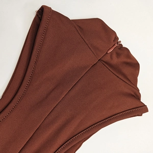 Détail de robe en maille marron foncé avec col montant, texture côtelée et fermeture éclair cachée