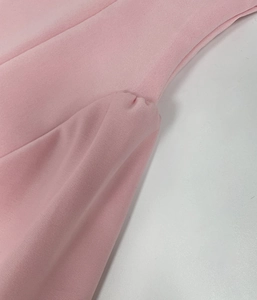 Detalle del vestido de punto rosa con elegantes fruncidos y textura plisada suave