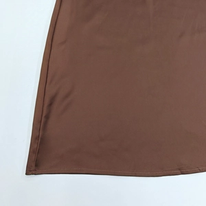 Gros plan de l'ourlet en satin marron montrant la texture lisse et les coutures nettes
