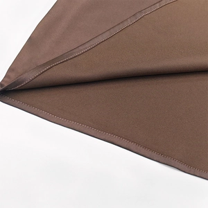 Gros plan des coutures invisibles et du tissu soyeux sur la robe moulante marron