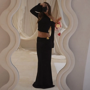 Detail of black off-shoulder set featuring ornate gold flower metal buckles on top and skirt