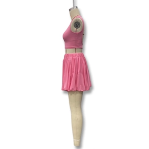 Detail view of pink two-piece set featuring backless crop top and pleated mini skirt