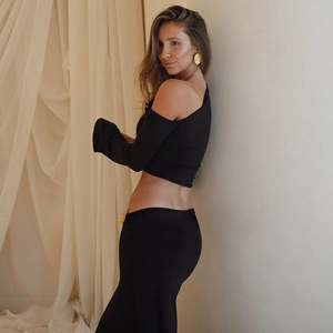 Detail of black off-shoulder top with gold metallic buckles and matching maxi skirt