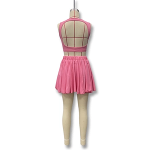 Detail view of pink two-piece set featuring a backless crop top and pleated mini skirt