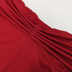 Détail du tissu en maille plissé rouge foncé montrant texture et éclat soyeux
