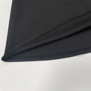 Close-up of double-needle hem stitching on a black A-line dress with smooth matte finish
