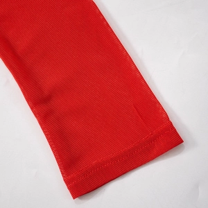 Detailed close-up showing the red sheer mesh fabric and flat-locked seam edge of the dress
