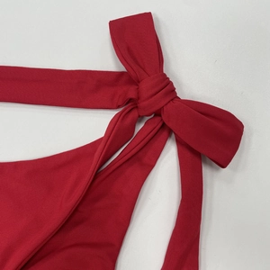 Gros plan détaillé du tissu côtelé rouge et du nœud élégant sur ce maillot de bain