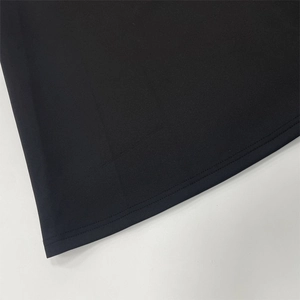 Detail shot of black knitted dress hem showing professional double-needle stitching quality