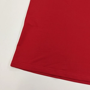 Gros plan de l'ourlet de la robe rouge montrant la double couture et le tissu en maille