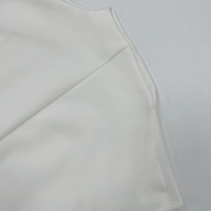Detailed view of stitching and smooth white fabric texture on a long sleeveless dress