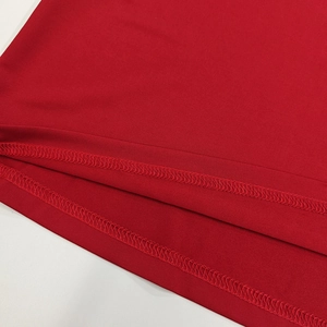 Gros plan d'une robe rouge avec couture à double aiguille sur le bord du tissu tricoté