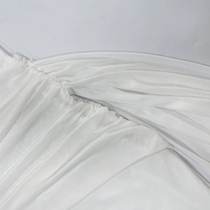 Vue détaillée du tissu en tulle blanc semi-transparent avec des plis et volants délicats