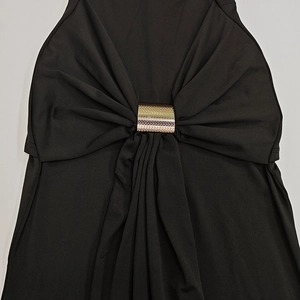 Detail of black off-shoulder dress with a central gold metal ring buckle and pleated fabric
