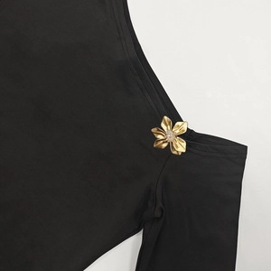 Close-up of elegant gold flower brooch with crystals on black off-shoulder top